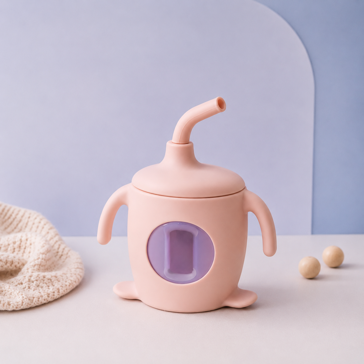 Pink sippy cup with a purple interior on a light blue background