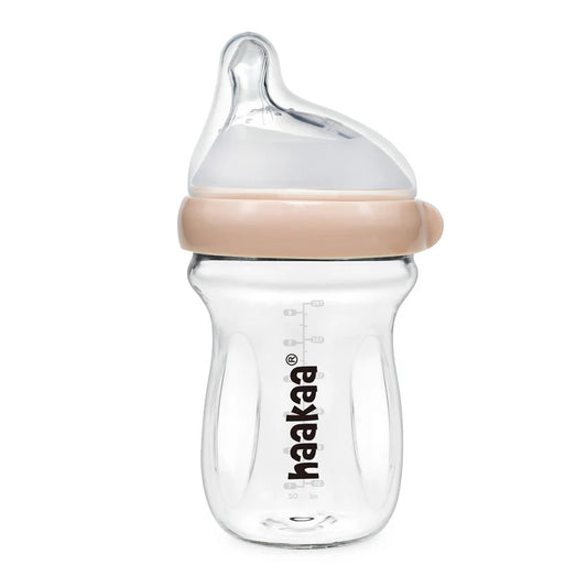 Clear baby bottle with beige cap and 'haakaa' branding on a white background