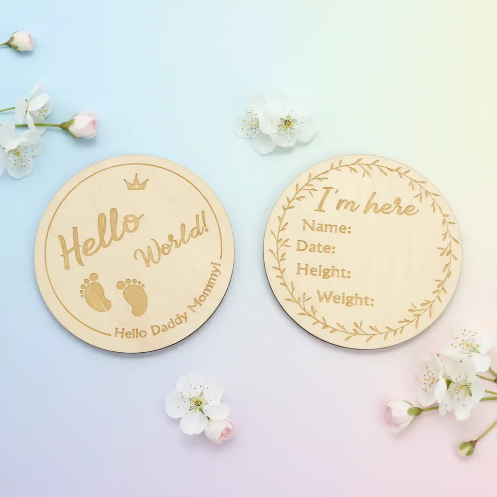 One says "Hello World!" with baby footprints; the other has "I'm here" with spaces for name, date, height, and weight, both.