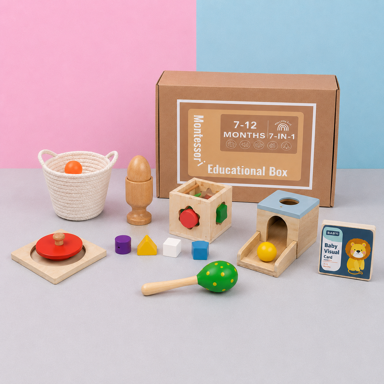 Montessori educational toy box set with wooden blocks, a basket, a maraca, a baby rattle card, and a brown cardboard box on a gray surface with a pink and blue background.