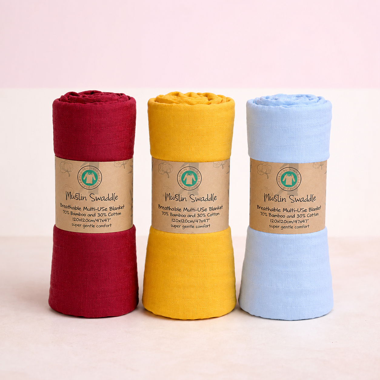 Three rolled-up cloths in red, yellow, and blue with visible branding on a light pink background.