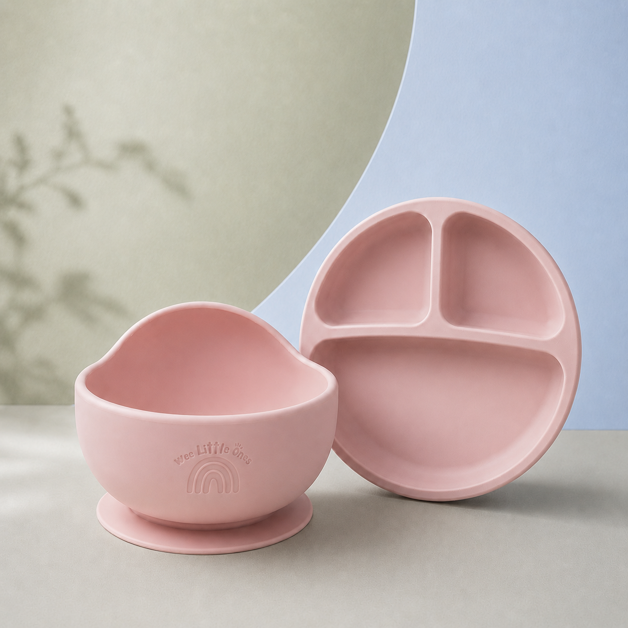 Pink silicone bowl and plate set on a neutral background