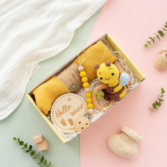 Baby gift set with plush toy, teether, and 'Hello world' plaque in a box on a light green background.