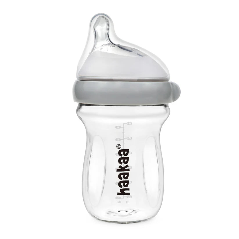 Clear baby bottle with gray cap on a white background, featuring the Haakaa brand.