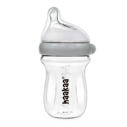 Clear baby bottle with gray cap on a white background, featuring the Haakaa brand.