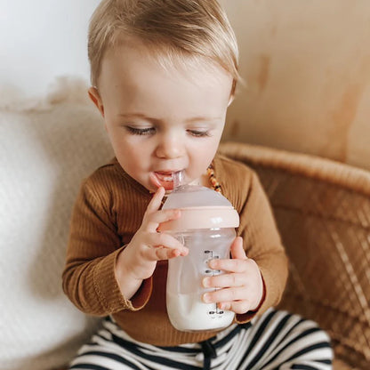 Child holding a bottle with a neutral background