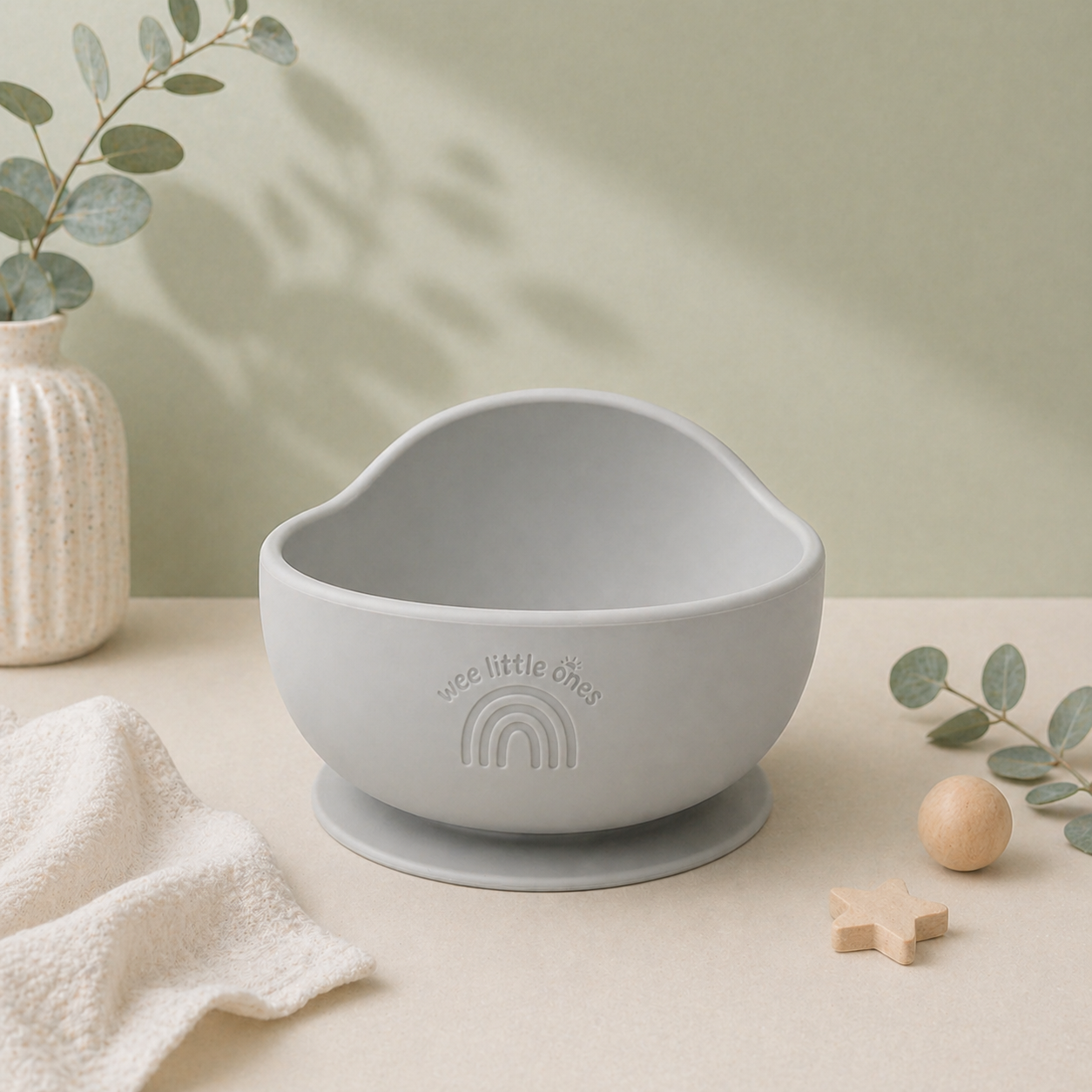 Gray bowl with suction cup on a beige surface with greenery