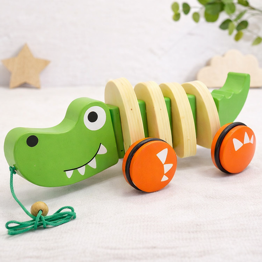 Wooden toy caterpillar with green body, orange wheels, and yellow body segments on a white surface.