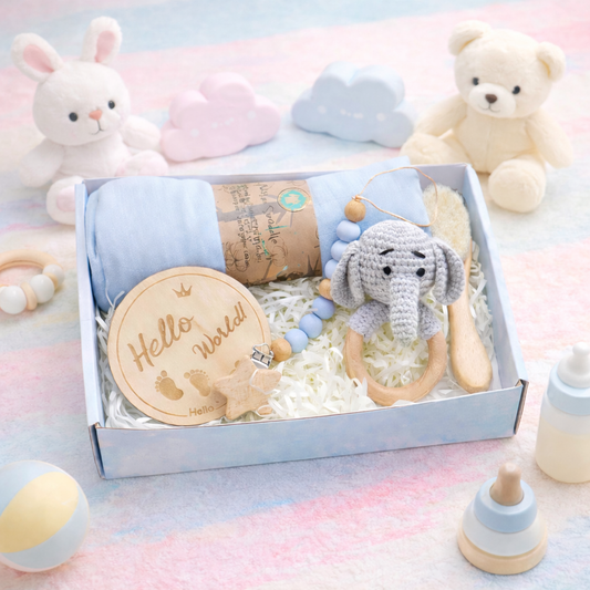 Baby gift set with toys and a blanket in a box on a soft surface.