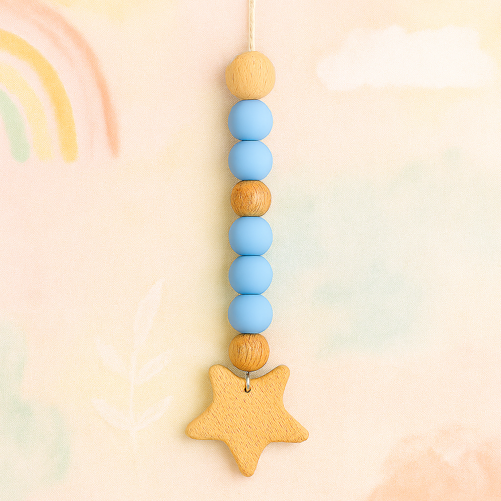Blue pacifier clip with round beads and a wooden star charm on a pastel background.