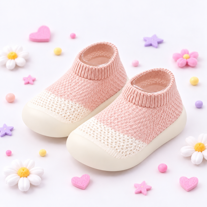 A pair of baby slip-on knit socks with cream-colored soles, styled on a white background with pastel decorative flowers, hearts, and stars.