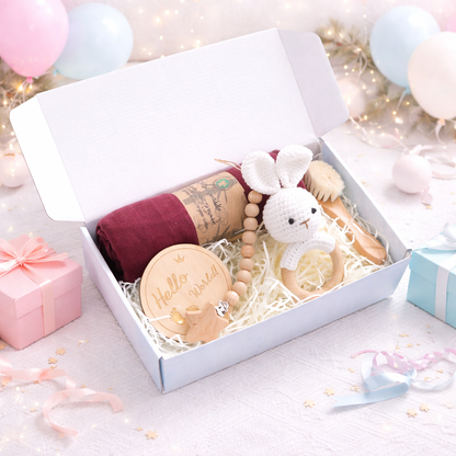 Baby gift set with items including a blanket, teether, and rattle in a box.