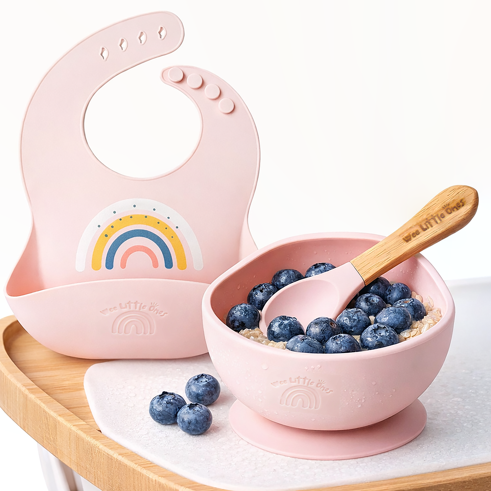 Pink baby bib and bowl set with blueberries on a white background