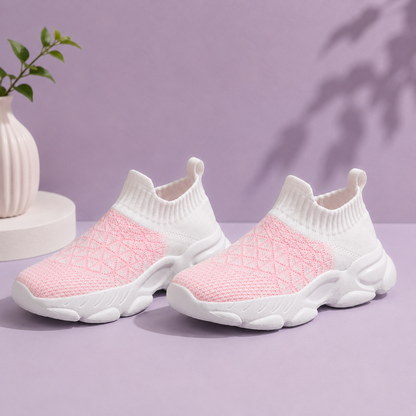 Pair of pink and white slip-on sneakers on a purple background with a plant.