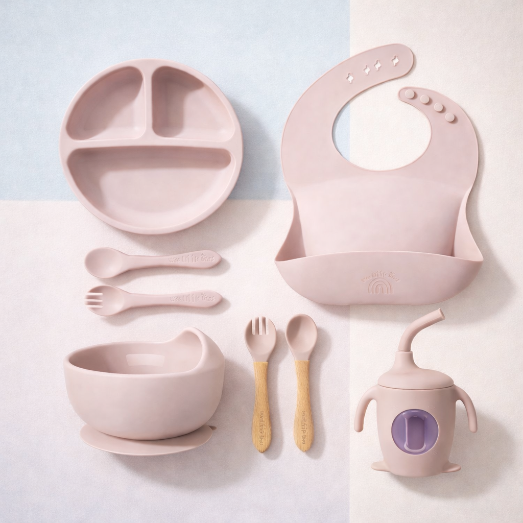 Pink children's dining set including plate, bowl, cup, and utensils on a light background