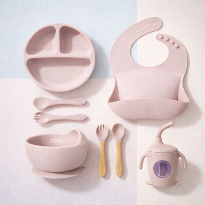 Pink children's dining set including plate, bowl, cup, and utensils on a light background