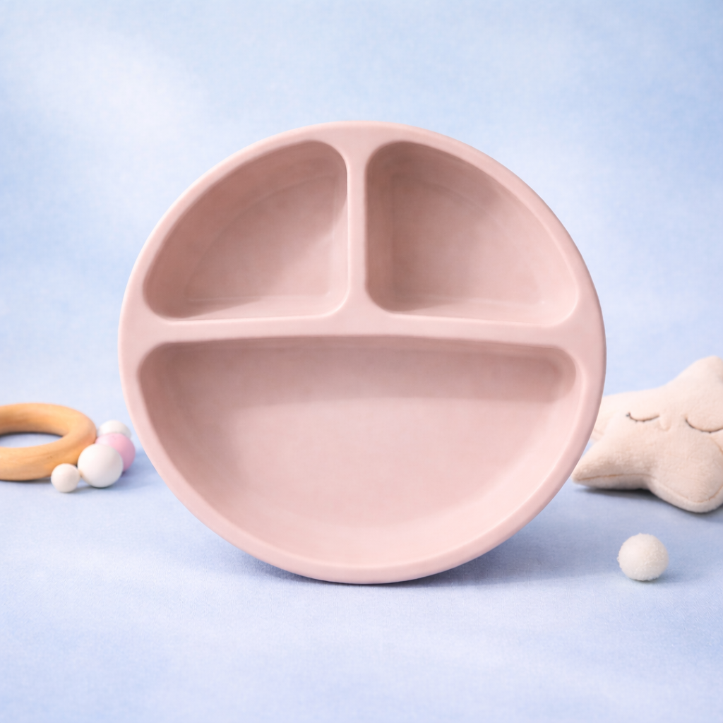 Pink children's plate with divided sections on a light blue background