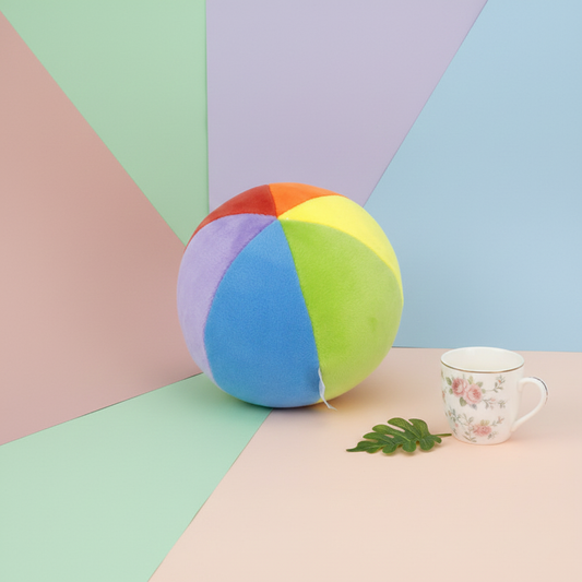 Colorful beach ball on a pastel geometric background with a mug and leaf.