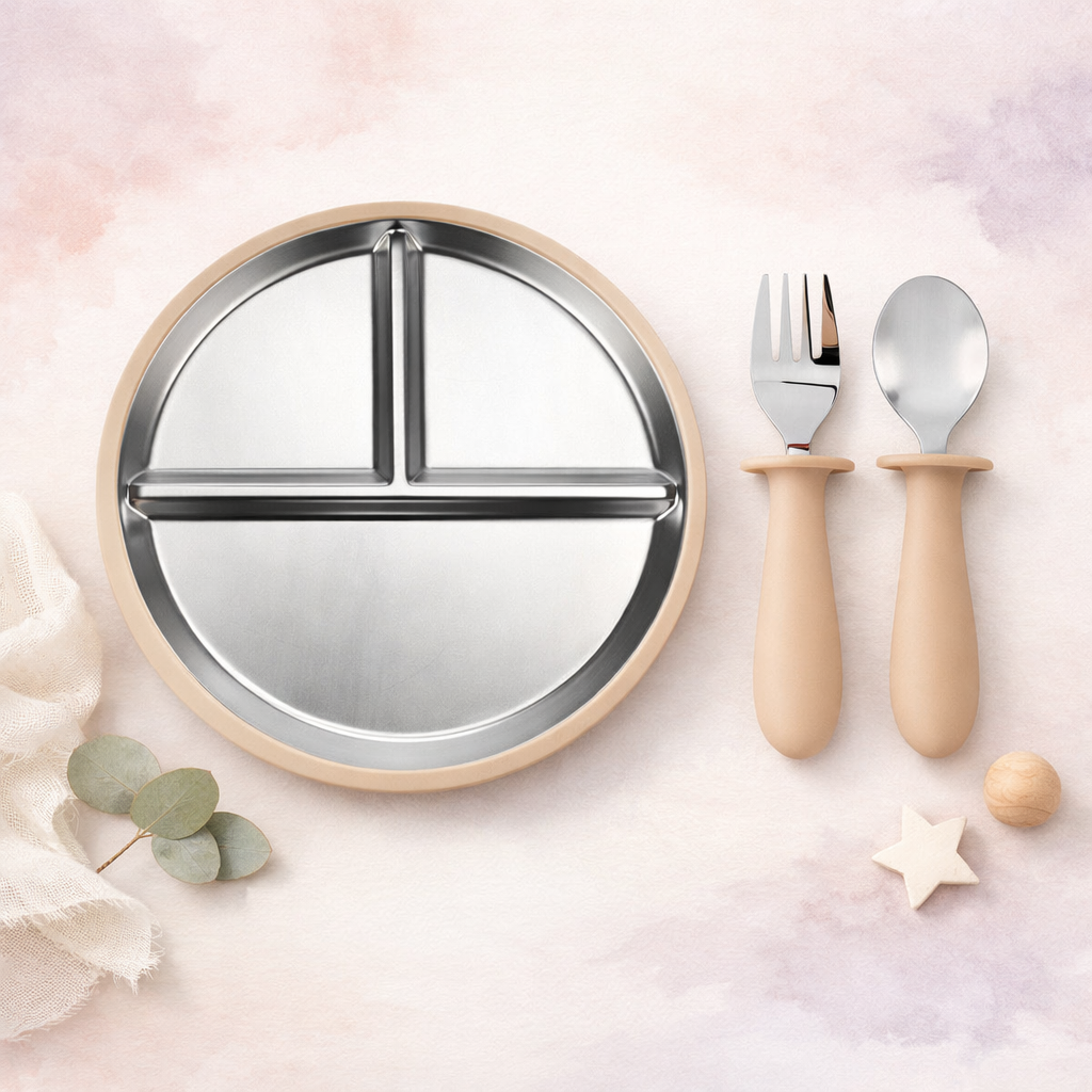 Round stainless steel plate with wooden handles and a fork, knife, and spoon on a light pink background.