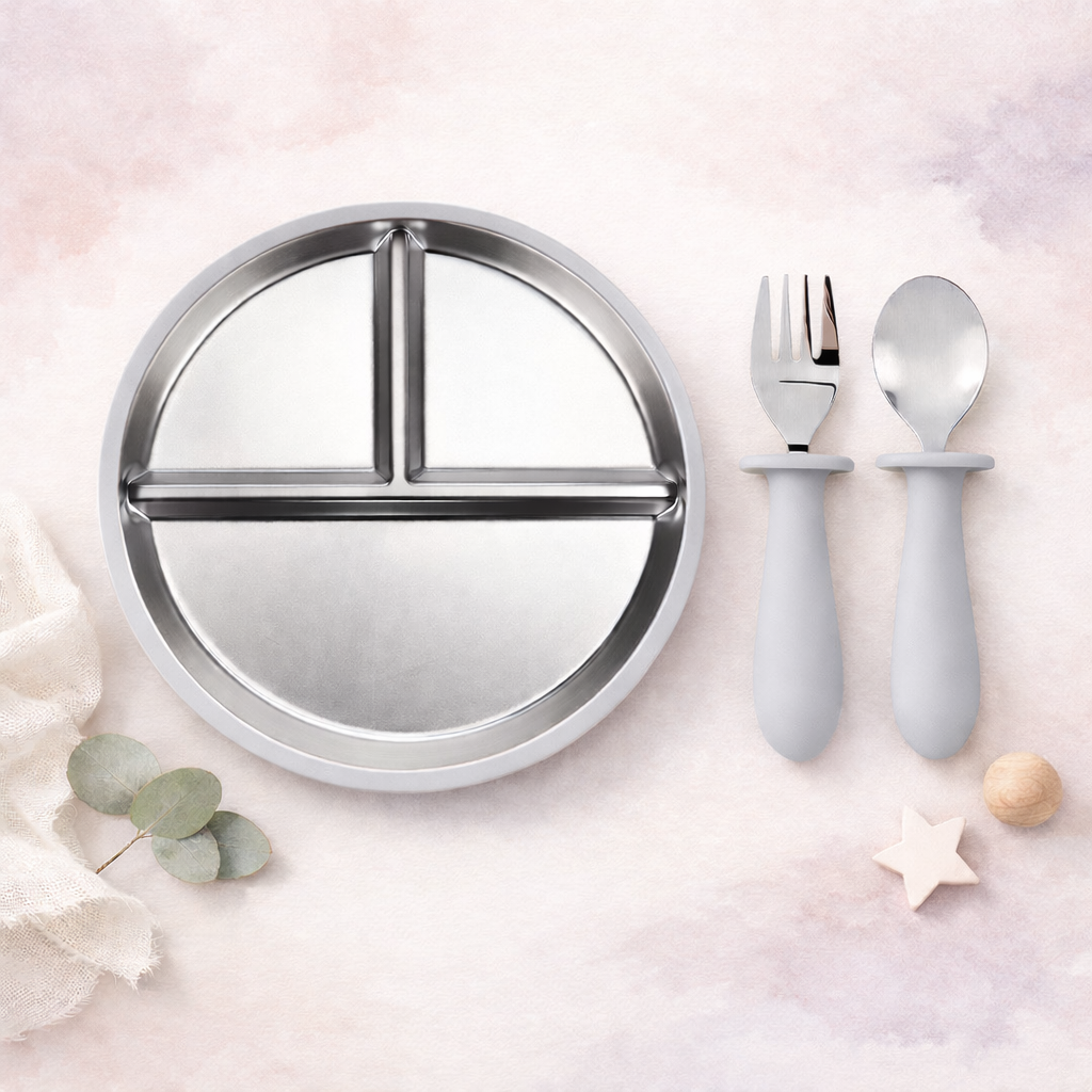 Round stainless steel plate with compartments and gray utensils on a light pink background