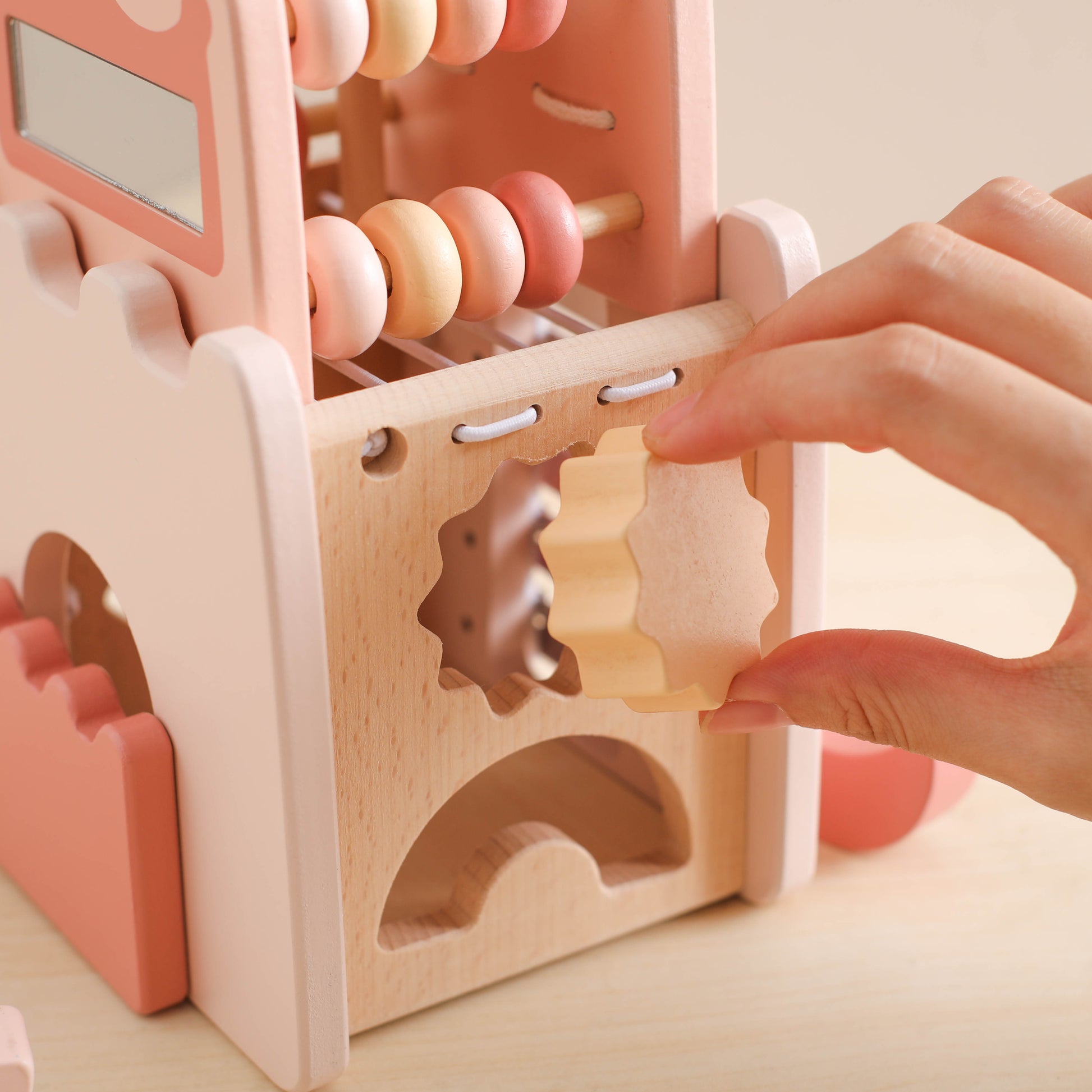 Wooden princess castle toy with pink and natural wood gears and abacus beads.