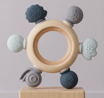 Baby teething ring with wooden center and silicone beads on a light gray background