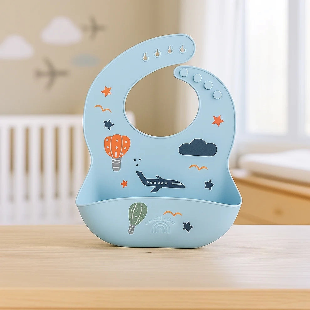 Blue silicone baby bib with airplane, hot air balloon, and star prints, adjustable neck buttons.