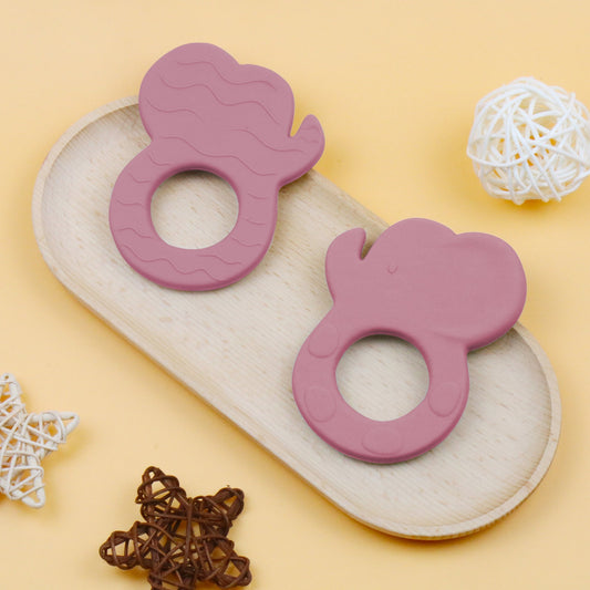 Red silicone elephant-shaped teether with textured surface and circular grip hole on tan tray.