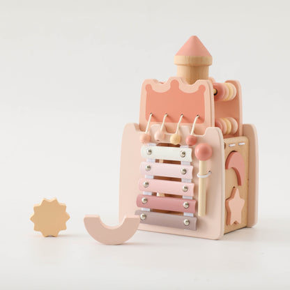 Wooden princess castle toy in pastel pink with xylophone and removable gears.